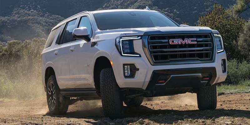 White 2023 GMC Yukon driving on rugged terrain