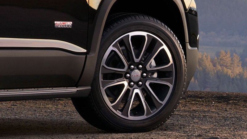 View of a GMC tire and wheel with the brake visible on a black GMC vehicle