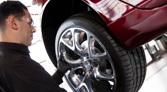 Buick Service Technician placing OEM tire on a red Buick vehicle